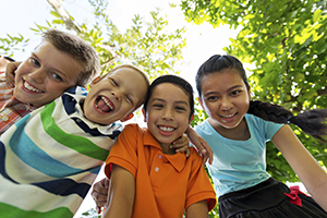 Four hugging and smiling children, view from below