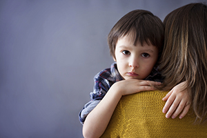 Sad little child, boy, hugging his mother at home, isolated image, copy space. Family concept