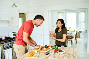 Husband preparing food in kitchen for pregnant wife