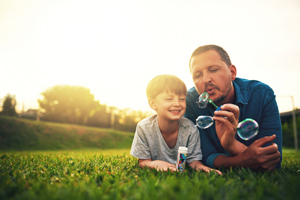 Shot of a father and his adorable son blowing bubbles in the backyard