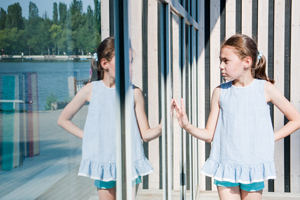 small cute girl looks at her reflection sunny day.