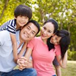 asian_family_with_two_children_taking_a_family_photo_outdoors_in_a_city_park