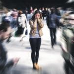 Woman overwhelmed with anxiety surrounded by people walking in busy street. Coping with anxiety, perfectionism, and ADHD.