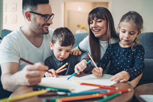 Two parents and a little boy drawing and writing together