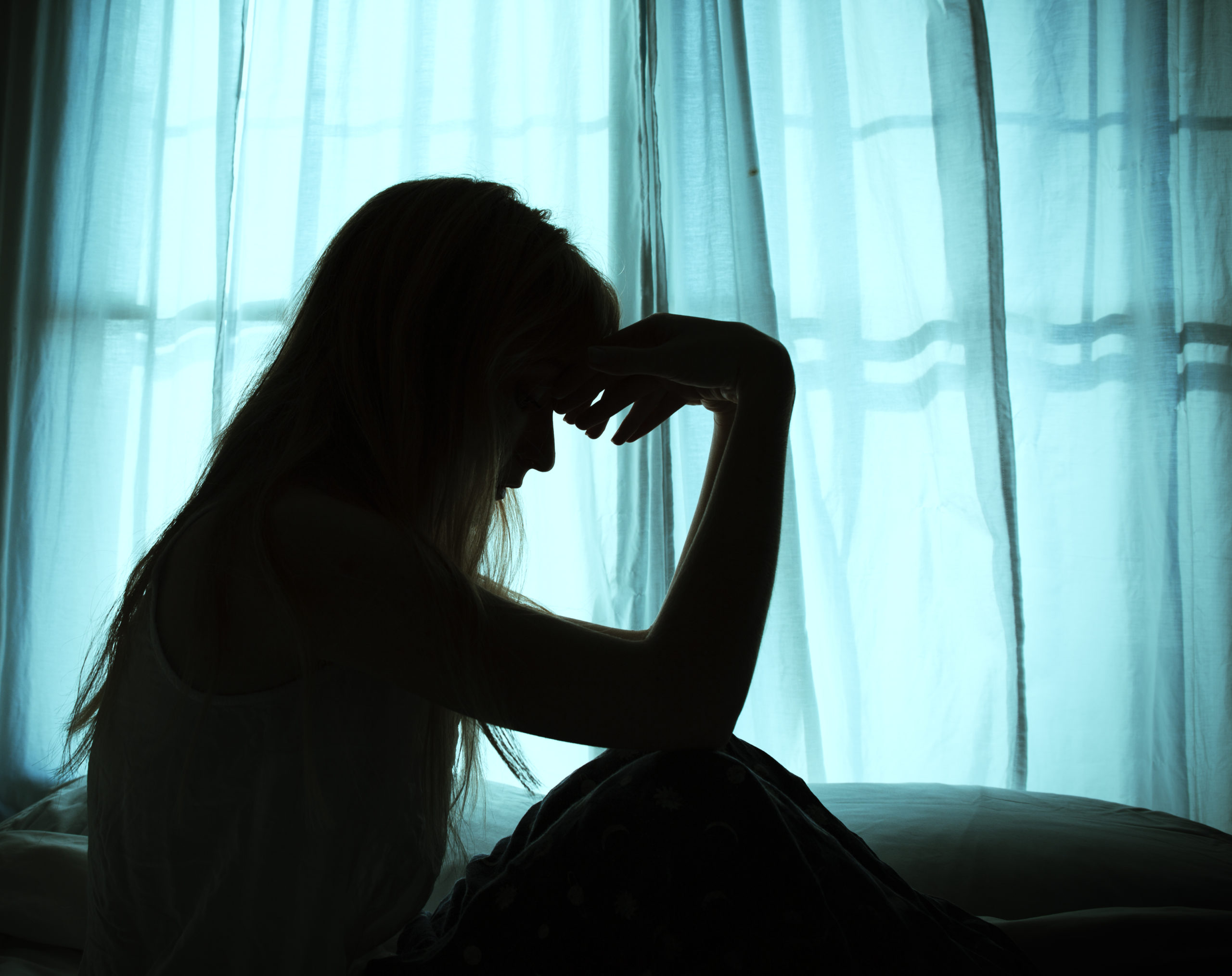 Silhouette of woman sitting in bed by window Silhouette of woman sitting in bed by window