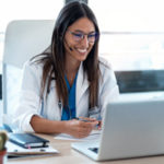 Shot of female doctor talking with colleagues through a video call with a laptop in the consultation.