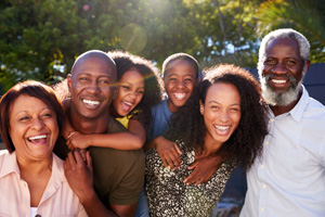 Outdoor Portrait Of Multi-Generation Family In Garden At Home Against Flaring Sun