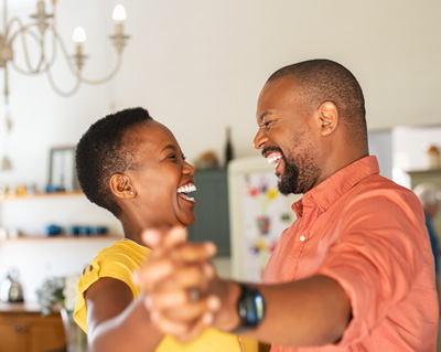 Cute mature couple dancing at home for their anniversary. Happy black woman enjoying a dance in the arms of her husband. Happy african couple dancing together in the kitchen and having fun together.