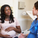 Pregnant Woman Meeting With Nurse In Clinic to discuss pregnancy