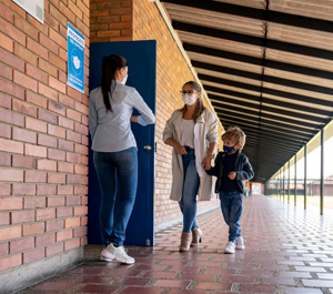 Teacher welcoming a student with her mother back to school and wearing facemasks - COVID-19 pandemic concepts