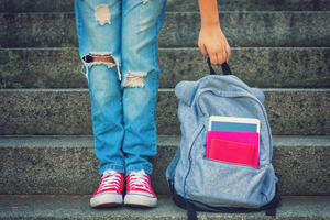 Young student girl with backpack staying on the stairs - back to school concept