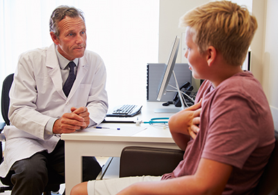 Teenage Boy Having Consultation With Doctor In Office