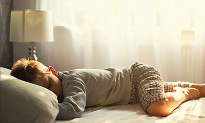 Young boy sleeping on his stomach on a bed. ADHD child sleeping soundly. ADHD and sleep.